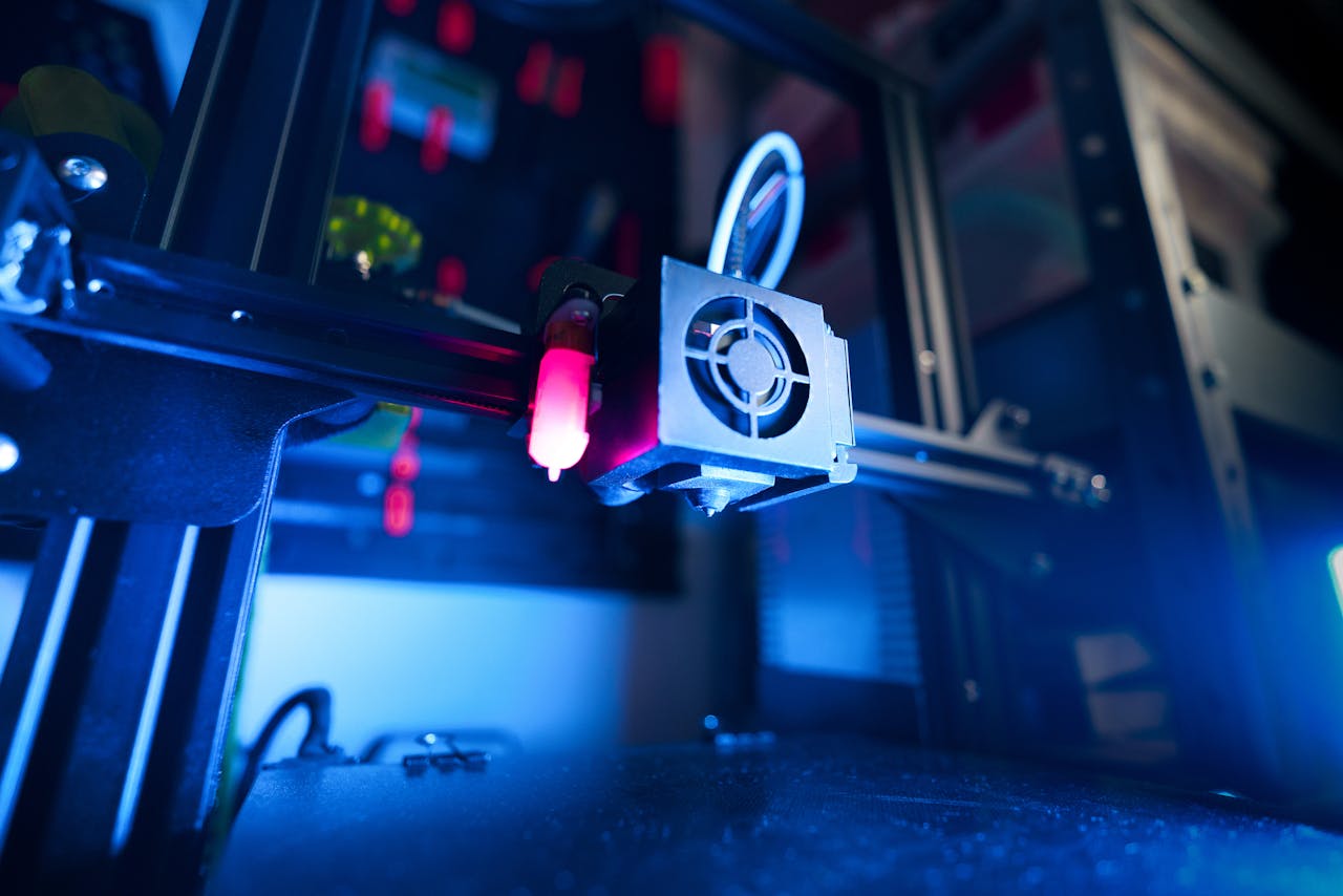 portfolio-02 A close-up of an illuminated 3D printer in action, highlighting modern technology.