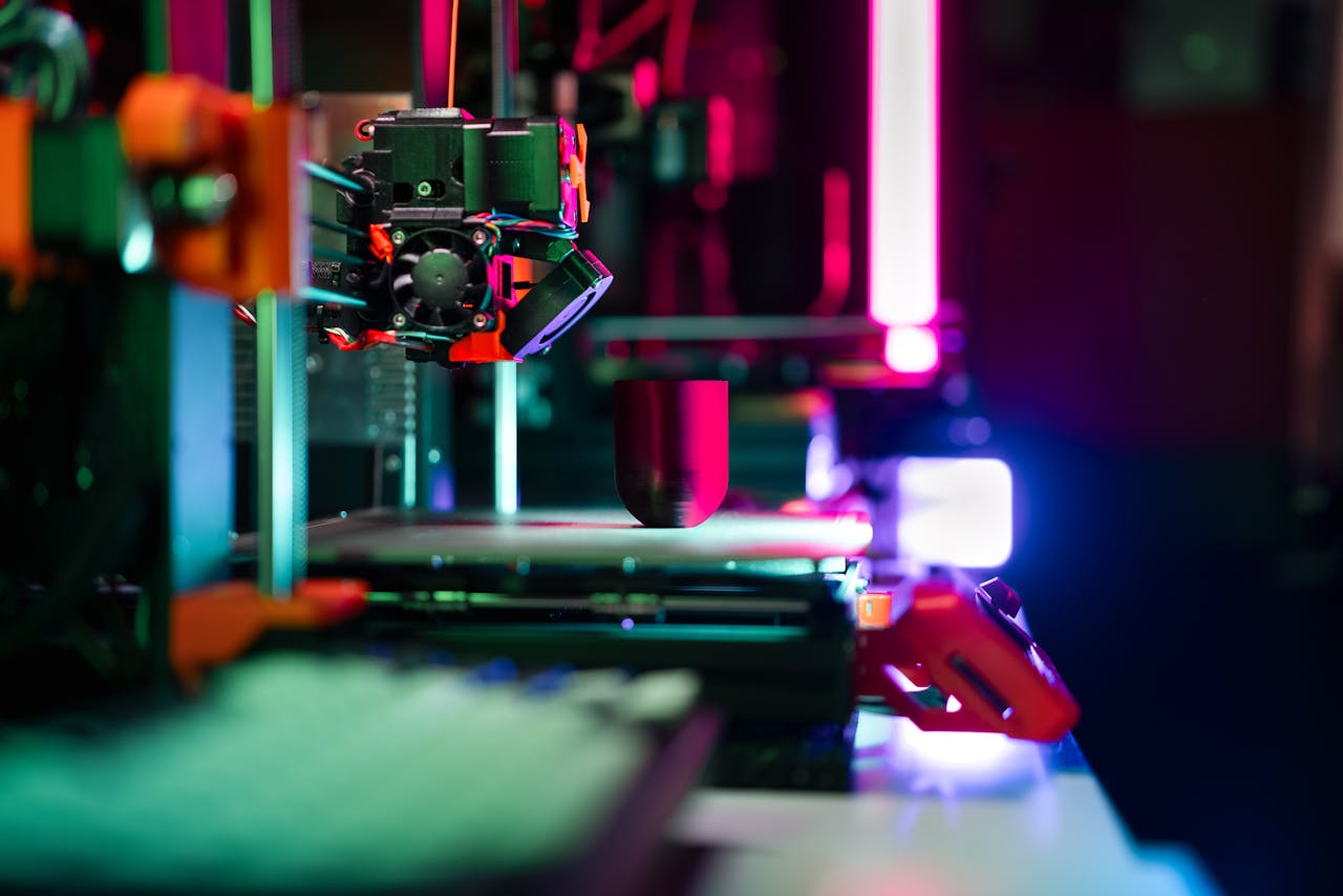 services-10 Close-up of a modern 3D printer in a workshop, highlighted by neon lighting.
